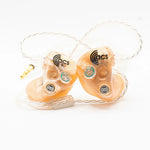 Pair of ACS earbuds in clear packaging on a white background