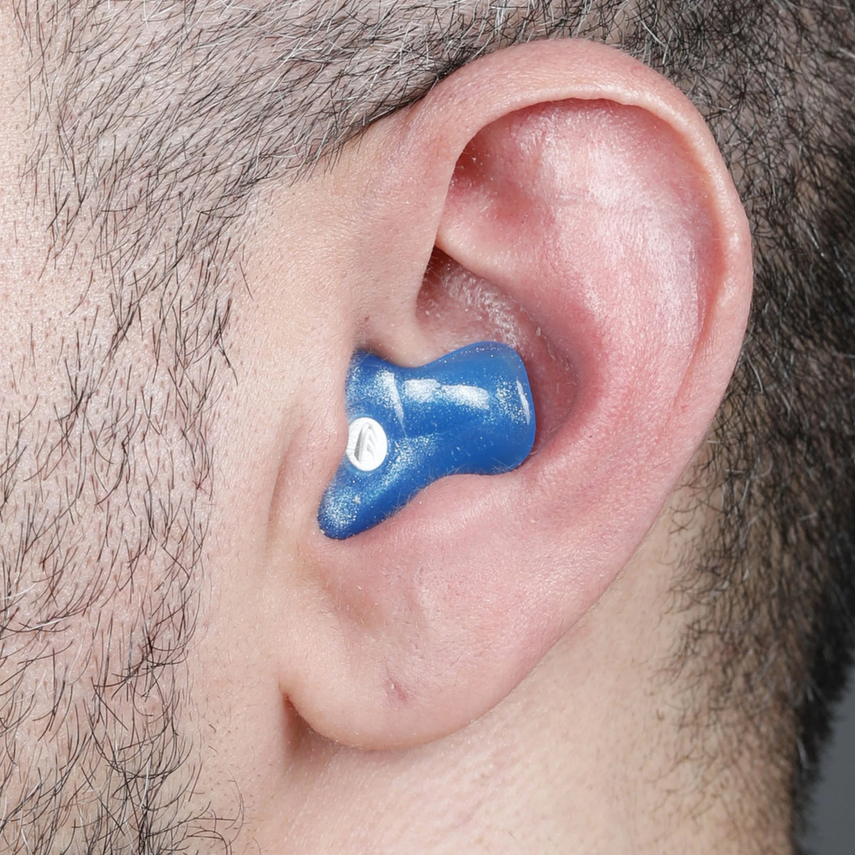 blue earplug in ear with dark hair around it