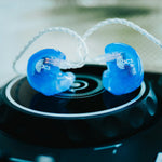 Blue earbuds with 'acs' logo on a black surface