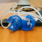 Blue earbuds with 'Engage' branding on a wooden surface