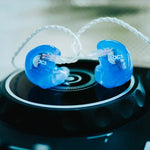 Blue earbuds with 'acs' logo on a black surface