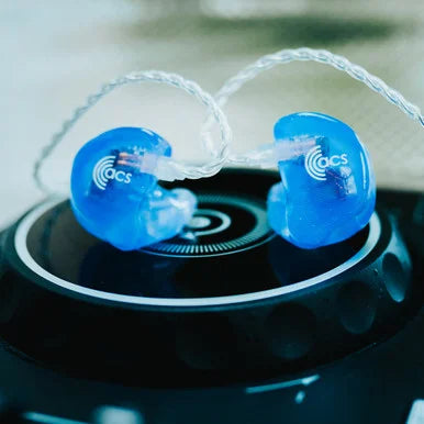 Blue earbuds with 'acs' logo on a black surface