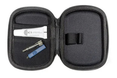 An open black zippered hard case showing its interior layout, containing a white tube labeled GCS, a small metal tool, and a blue accessory, photographed on a white background.