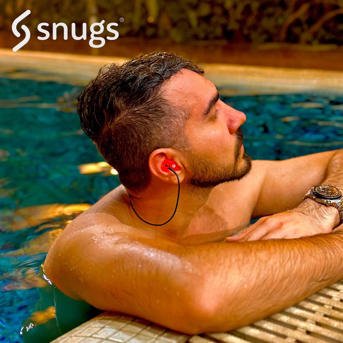 man with red earplugs in his ears with some cording attached whilst sitting in a swimming pool