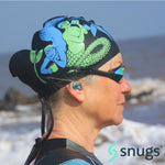 multi coloured earplugs in women's ears whilst wearing a swimming cap with the sea in the background