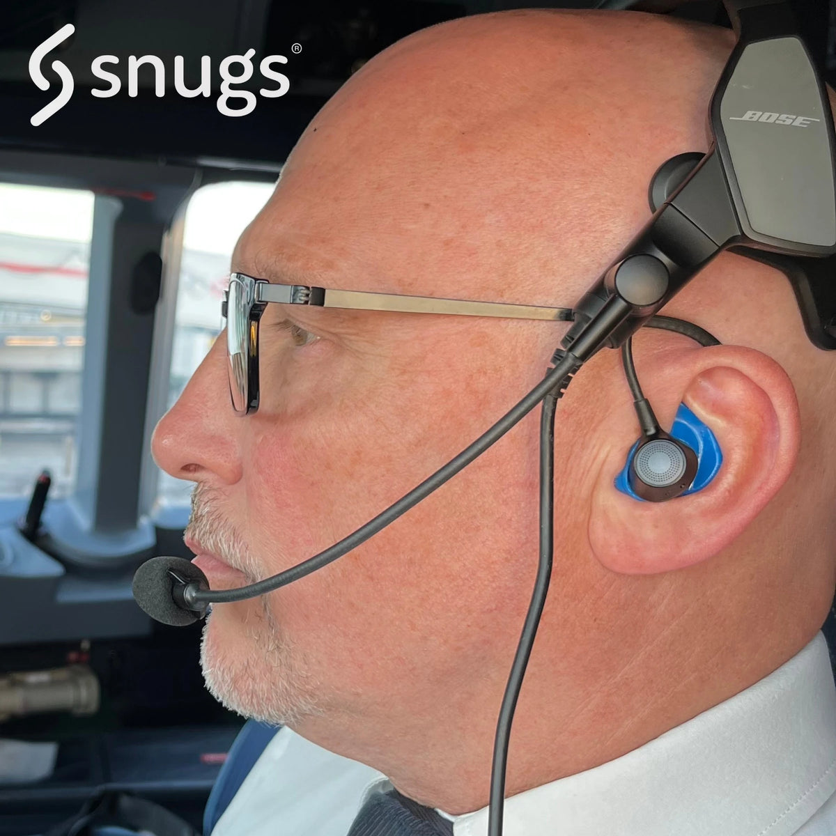 man wearing Bose aviation headset with snugs earplugs whilst flying plane