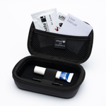 A black zippered carrying case shown open on a white background, containing a small white-and-blue tube, two black tools, and printed inserts including a user manual and a brand card.