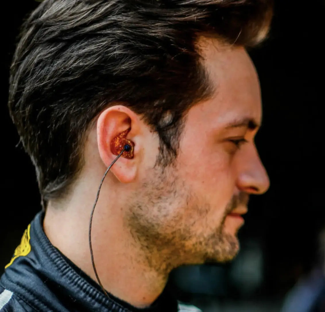 men wears glitter red earplugs in his ears with dark shirt on