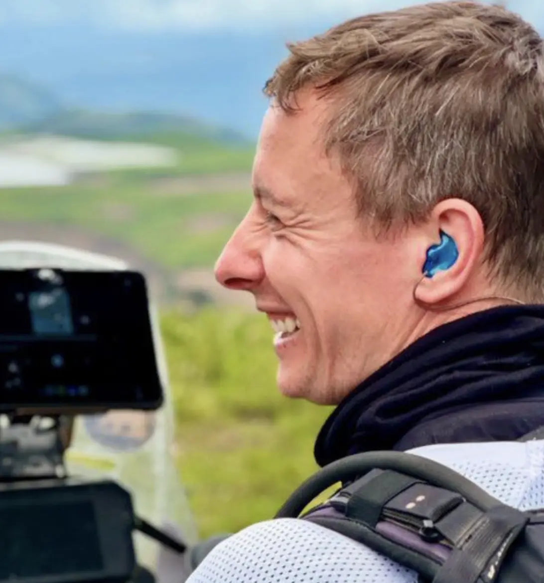 Person wearing blue earplugs in a vehicle with a scenic background