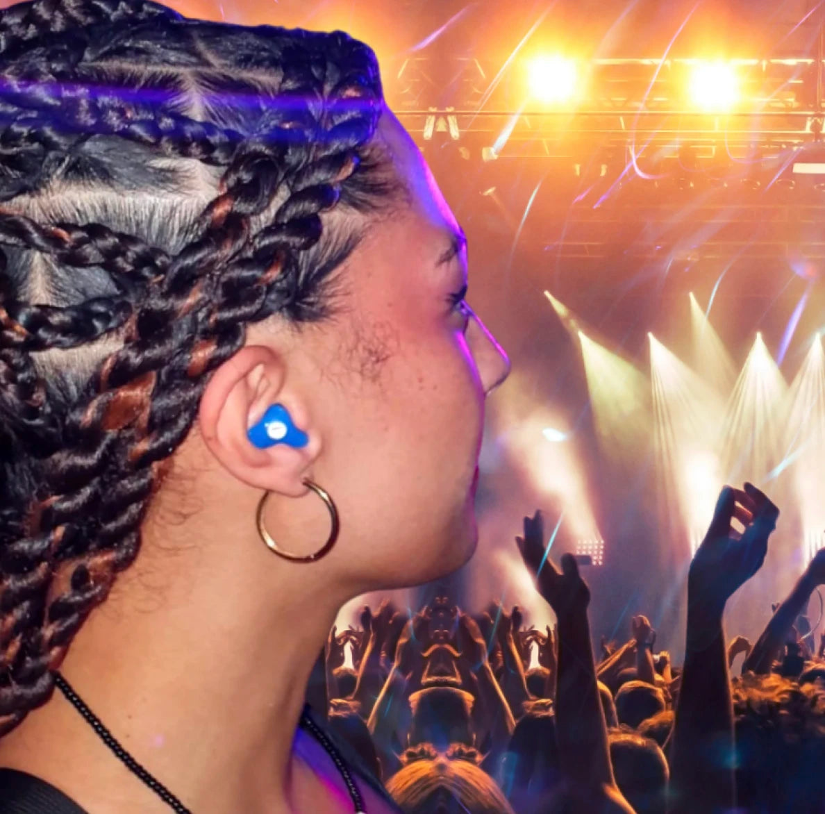 Person with braided hair at a concert with bright lights and raised hands.