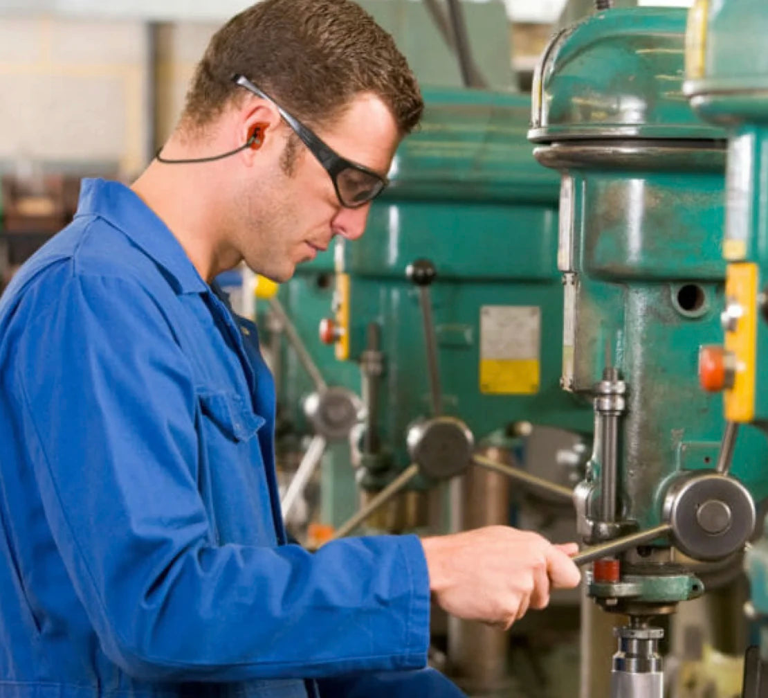man operating drill with orange earplugs in